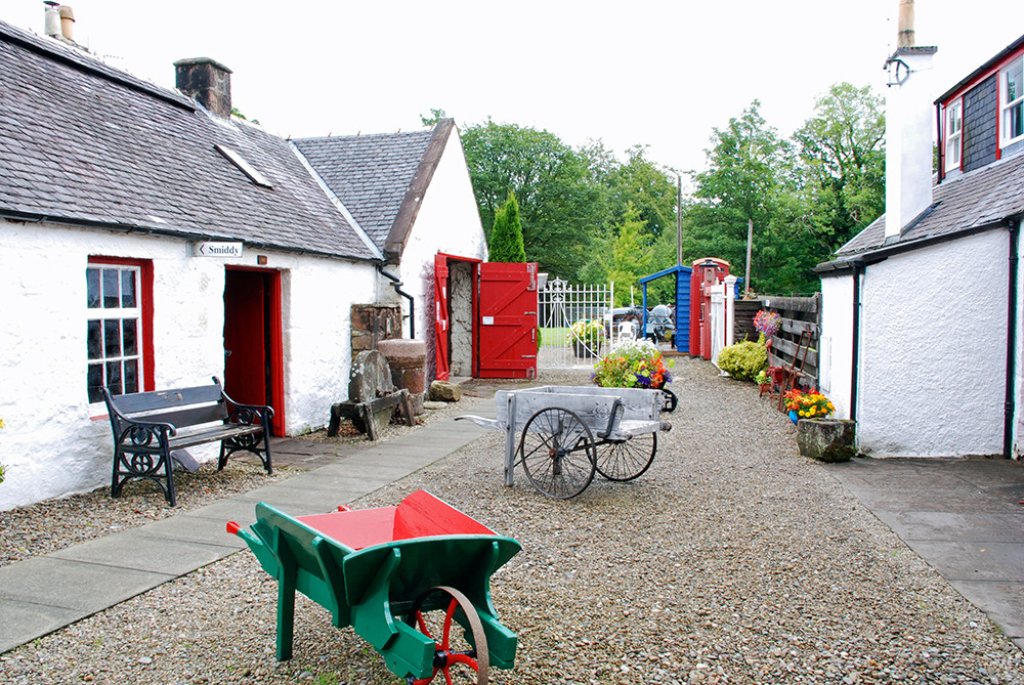 White-washed Isle of Arran Heritage Museum building with red-framed windows and entrance.