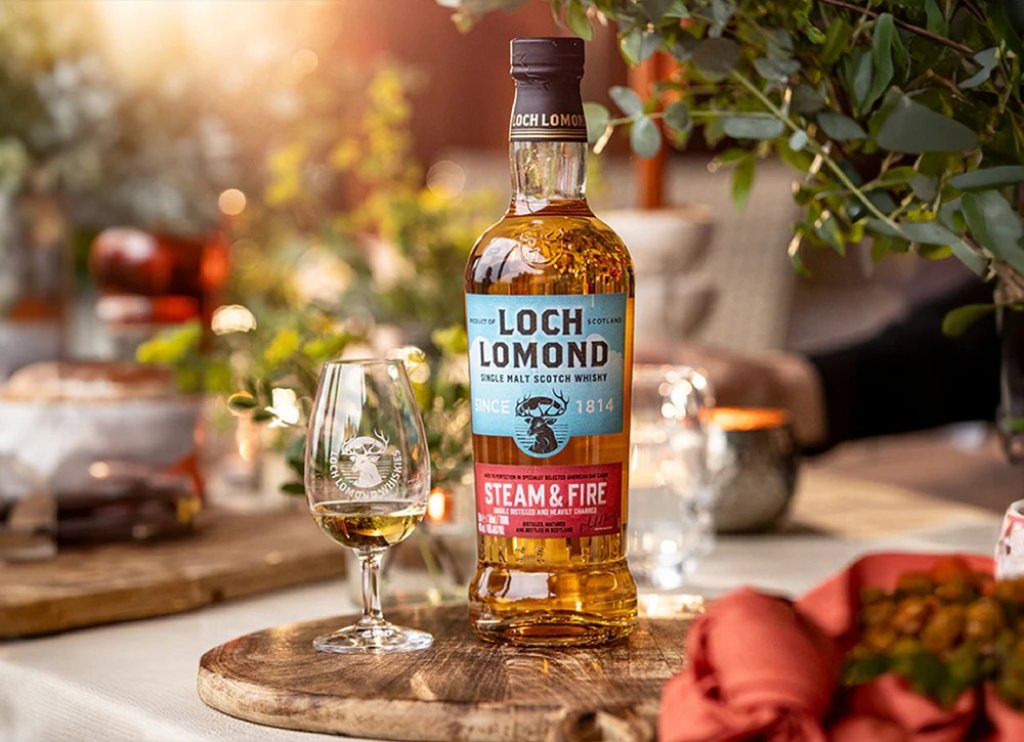 A bottle of Loch Lomond whiskey sat on a table next to a glass of Loch Lomond whiskey.