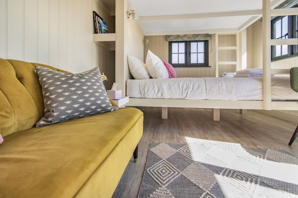 Comfortable sofa and bunk bed inside a shepherd's hut.