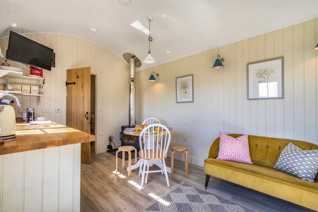 A log burner is lit and the breakfast table is laid in a cosy shepherd's hut in Scotland.