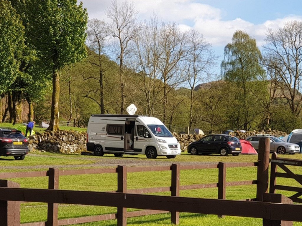 A campervan is parked up next to cars and tents in the Beinghlas.