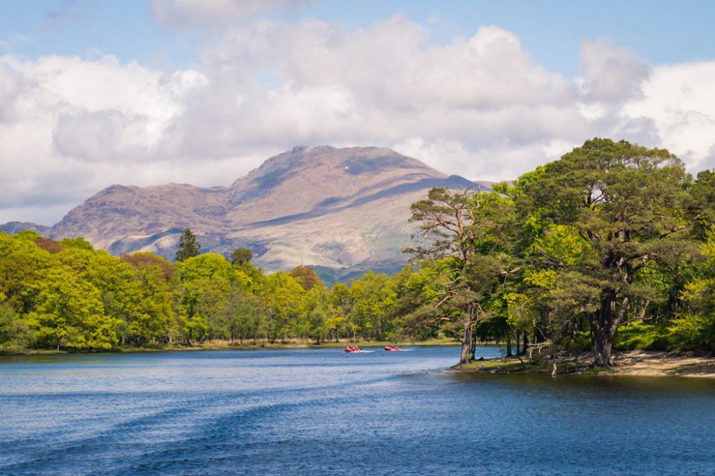 Kayaks are passing by in the distance, of a beautiful view from the riverside at Ben Lomond.