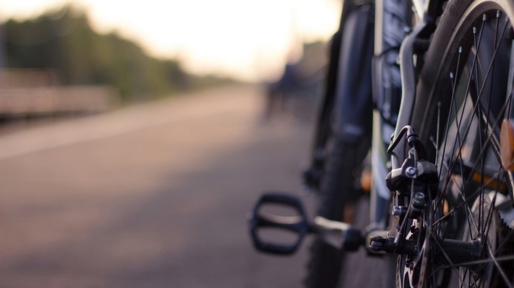 A close-up of a bike wheel on a country road.