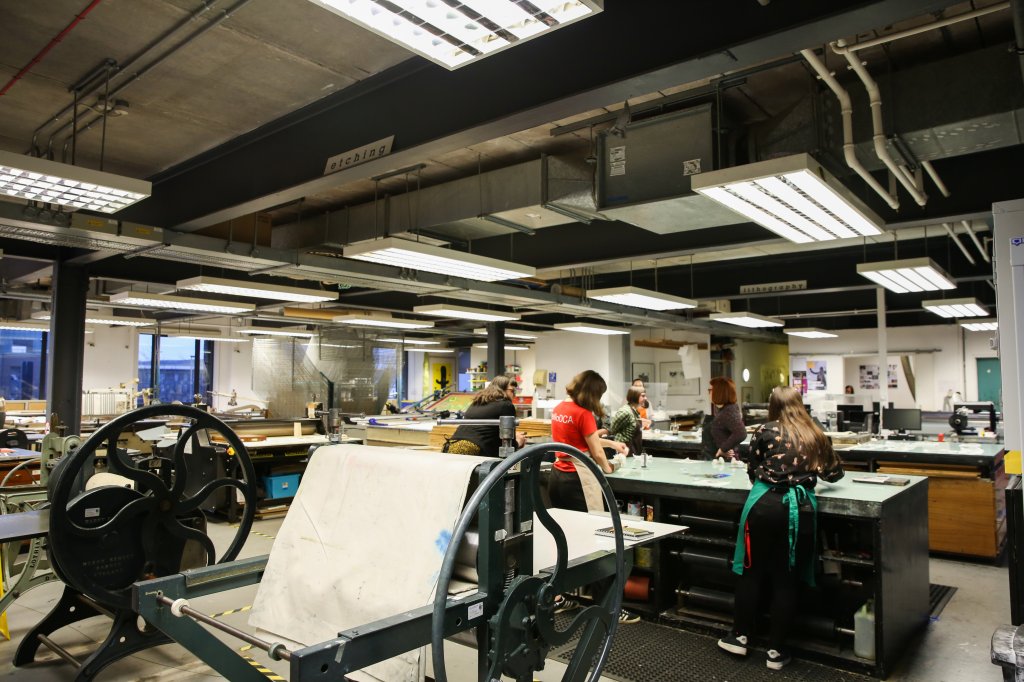 a room in a warehouse, filled with old printing presses and being used today by a group of women.