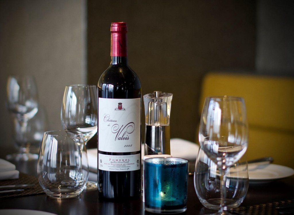 a glass of wine sat on a table surrounded by wine glass.