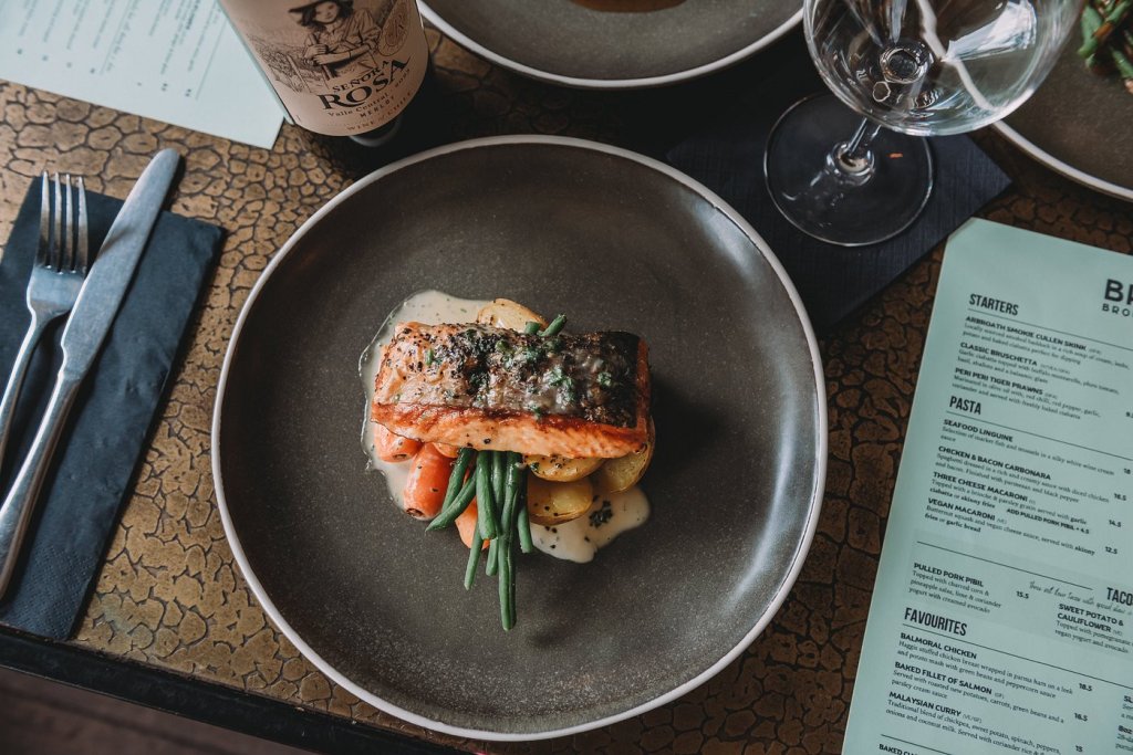 A plate of delicious looking salmon on a bed of carrots, green beans, and potatoes.