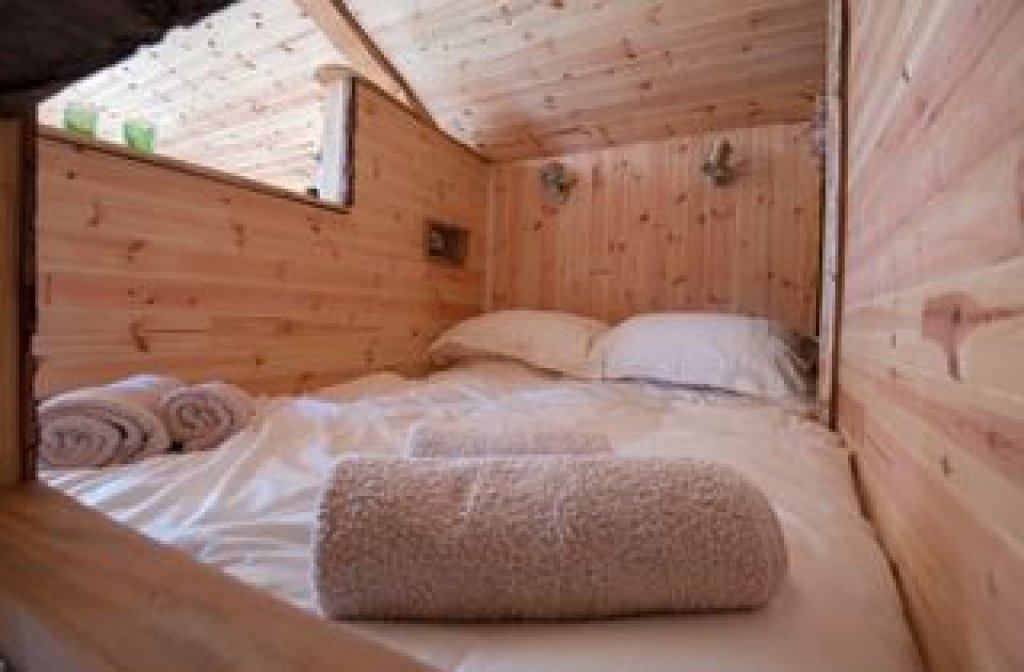 A cosy cabin double bed is made up with fresh linen sheets and towels ready for guests.